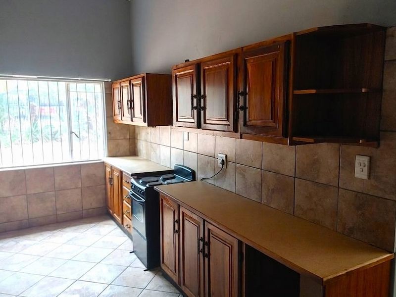 A functional kitchen featuring wooden cabinetry, tiled backsplash, and a freestanding stove, offering a practical layout with potential for modern updates.