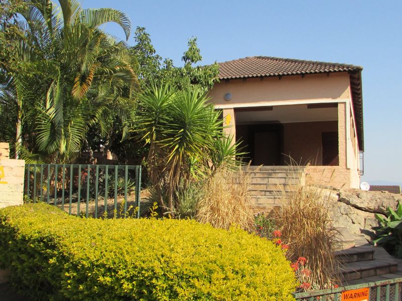 Front exterior view of the townhouse featuring a covered entrance, concrete stairs, and established garden landscaping.