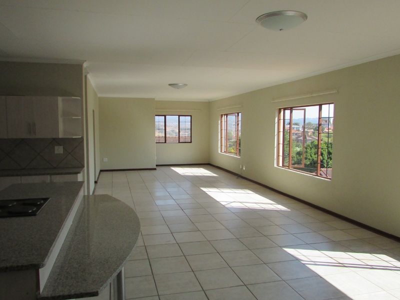 Spacious open-plan living and kitchen area featuring tiled flooring, granite countertops, built-in hob, and large windows providing ample natural light and scenic views.