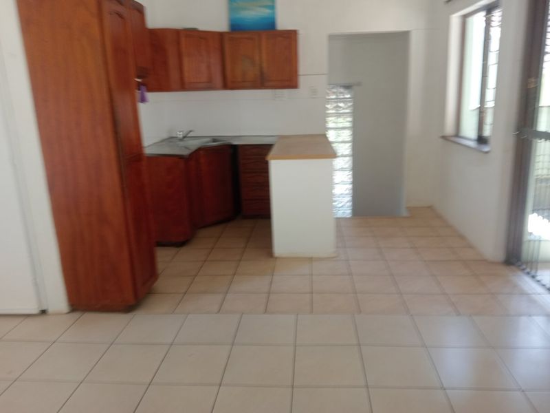 A functional kitchen area featuring wooden cabinetry, laminate countertops, and tiled flooring, offering a blank canvas for potential modern updates.