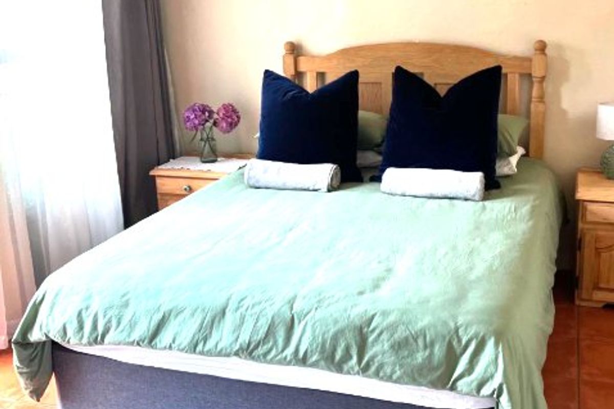 A bedroom featuring terracotta floor tiles and a window with a curtain rod.