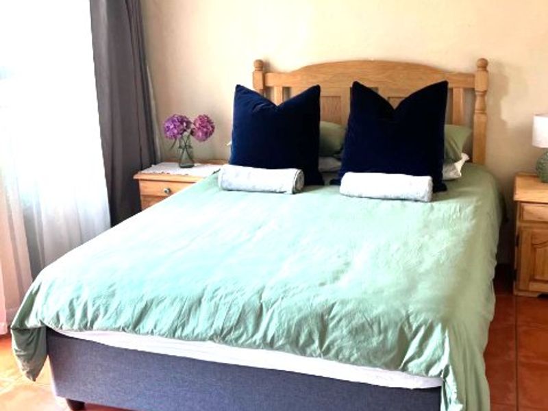 A bedroom featuring terracotta floor tiles and a window with a curtain rod.