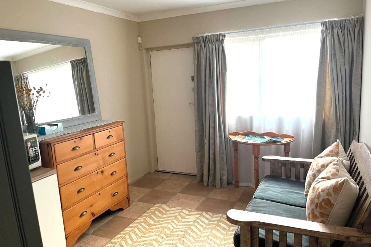 A living area featuring tiled flooring, coving, and a security alarm sensor, providing a functional space with natural light from the window.