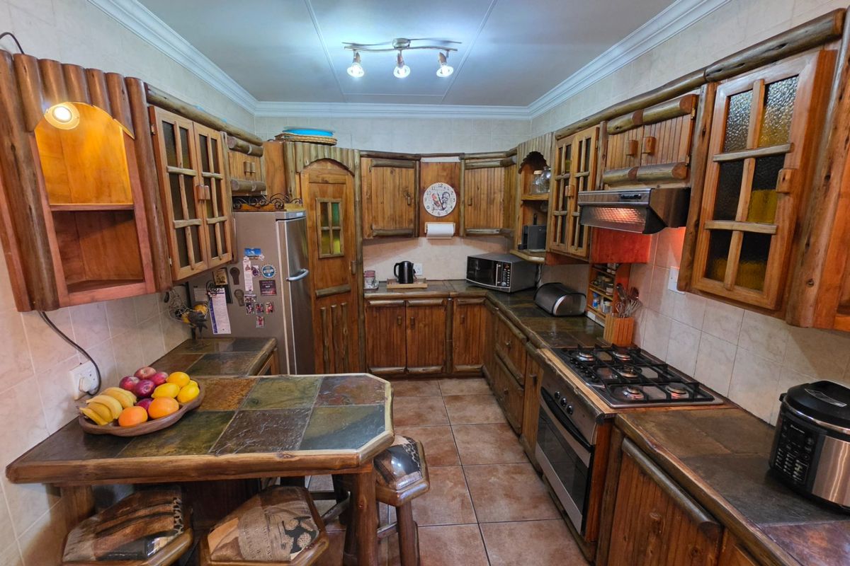 A rustic-style kitchen featuring custom wooden cabinetry, stone tile countertops, a gas hob, built-in oven, and tiled flooring throughout.