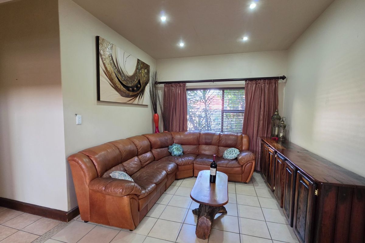 A comfortable living room featuring tiled flooring, recessed downlighting, and custom built-in wooden cabinetry, offering a functional and inviting space.