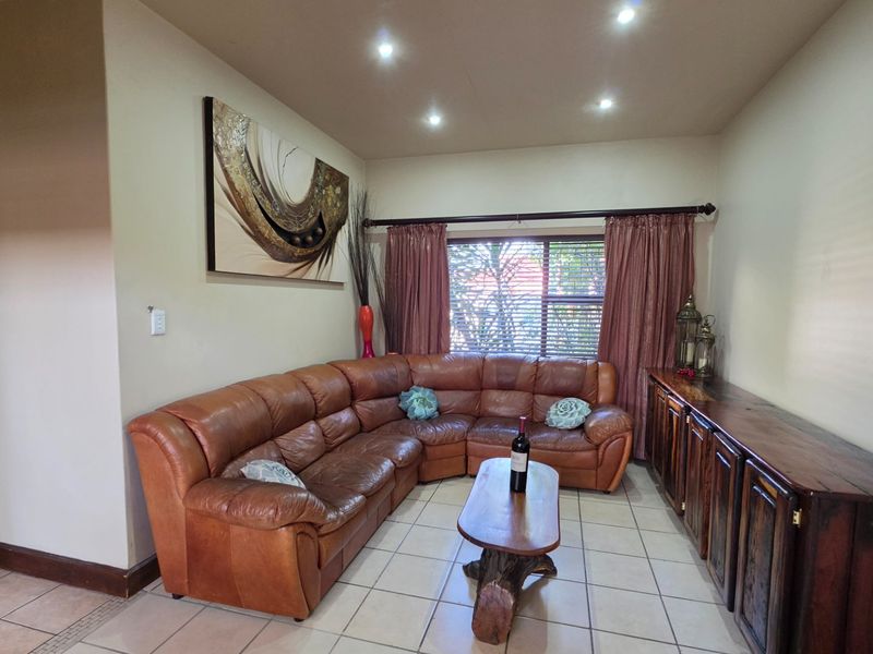 A comfortable living room featuring tiled flooring, recessed downlighting, and custom built-in wooden cabinetry, offering a functional and inviting space.