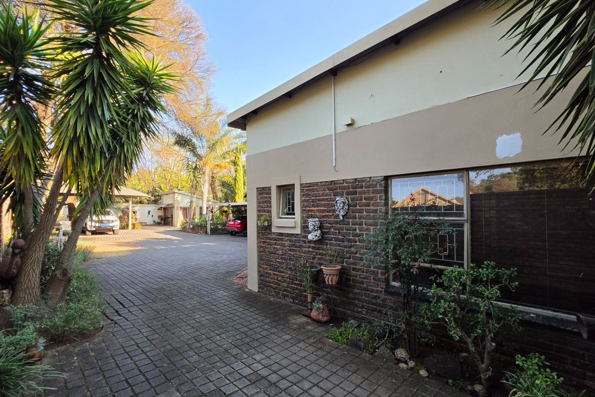 A view of the rear exterior area featuring brick paving, a combination of facebrick and plastered walls, and secure window fixtures.