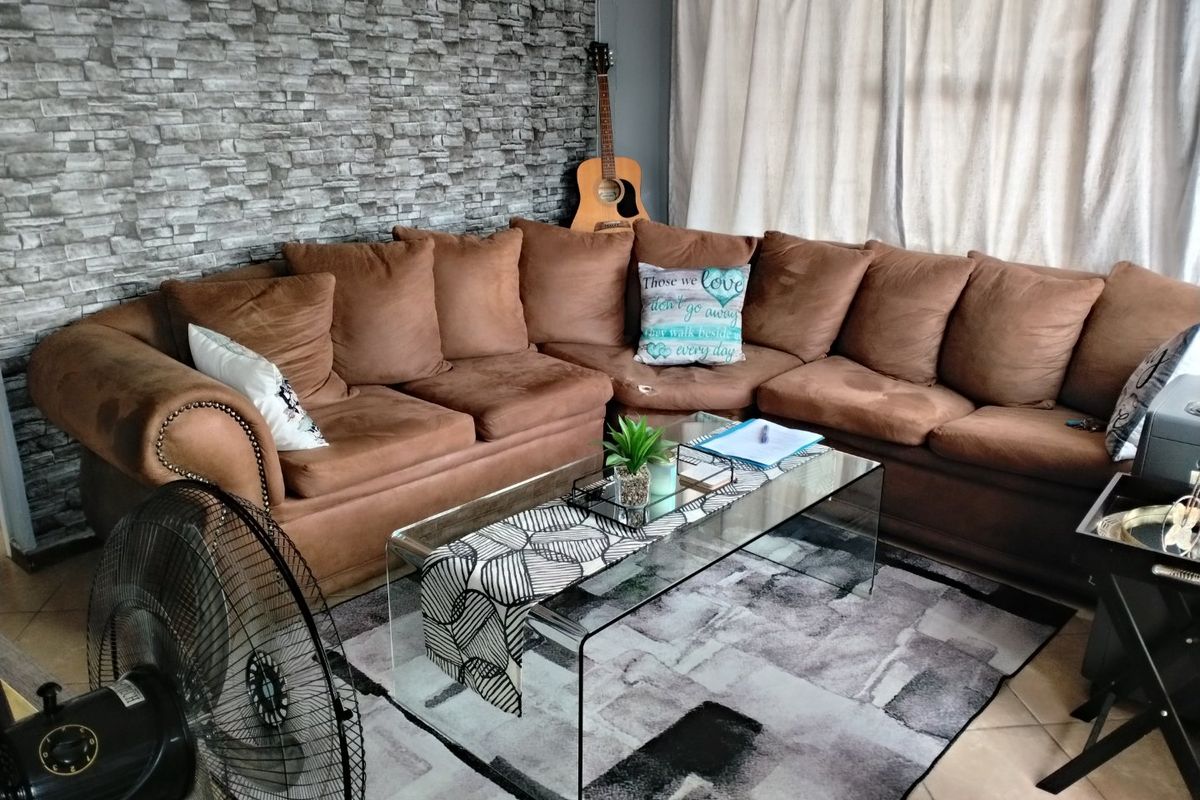 A living room featuring a textured stone-cladding accent wall and neutral tiled flooring, providing a foundation for a modern interior design update.