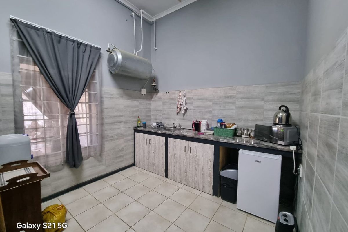 A functional kitchen area featuring built-in cabinetry, tiled backsplash, and tiled flooring, with an exposed wall-mounted water heater.