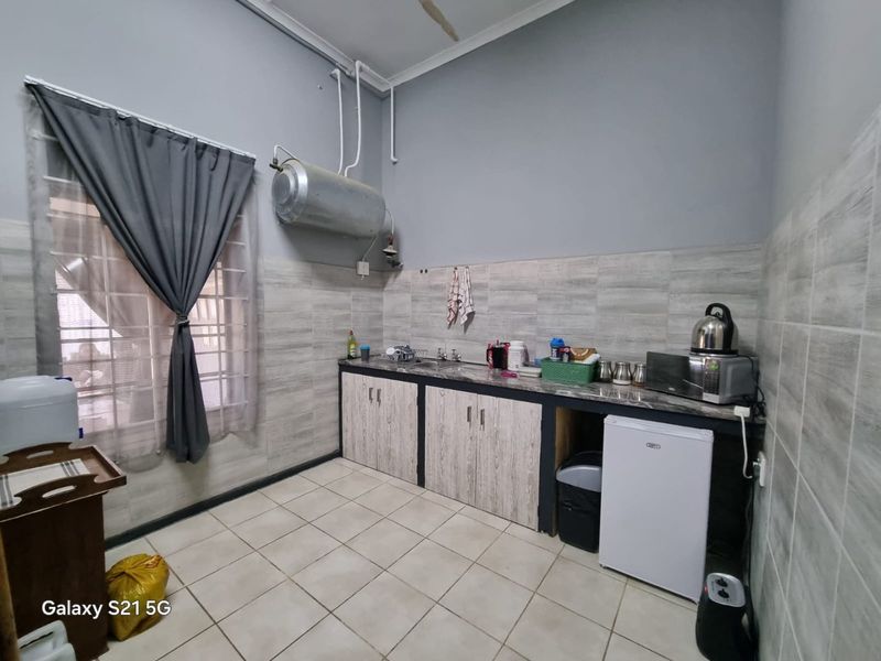 A functional kitchen area featuring built-in cabinetry, tiled backsplash, and tiled flooring, with an exposed wall-mounted water heater.