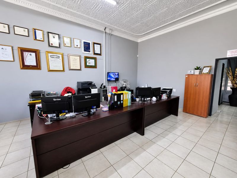 A professional office space featuring tiled flooring and a decorative pressed metal ceiling with crown molding.