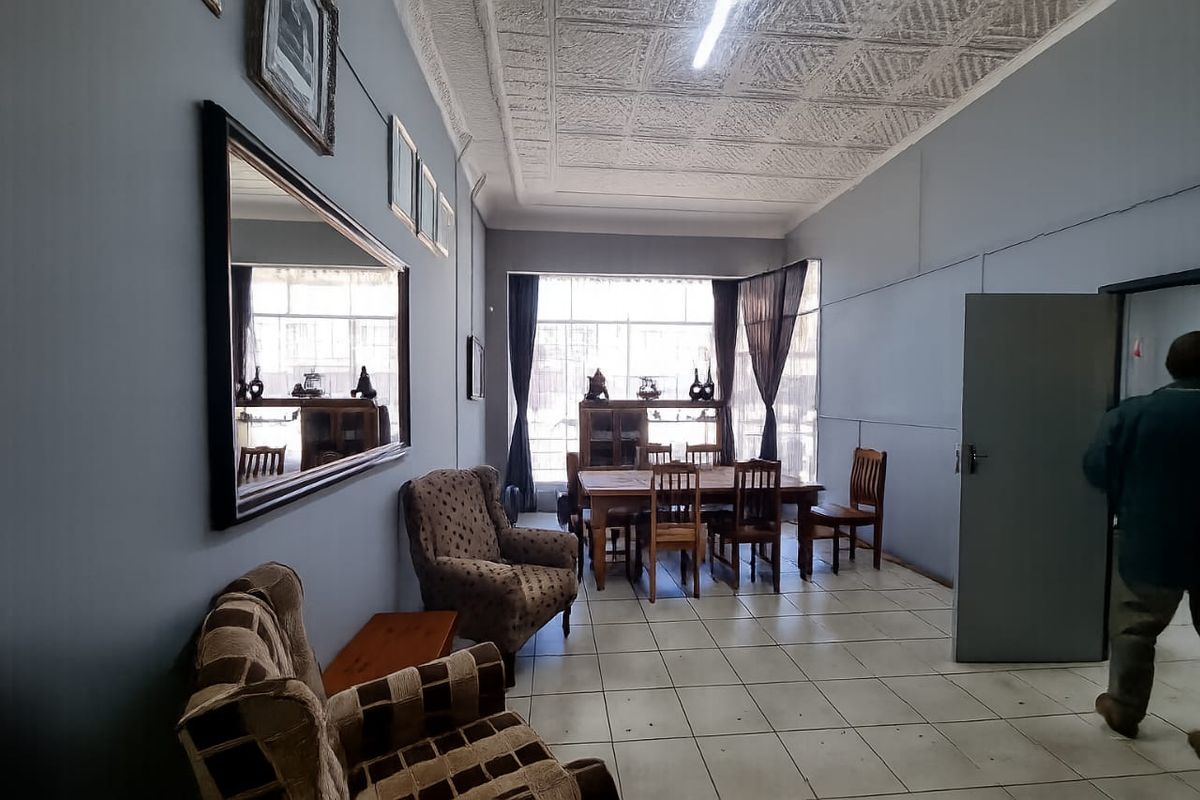 A spacious living area featuring tiled flooring and a textured ceiling, offering a functional layout with natural light from a large window.
