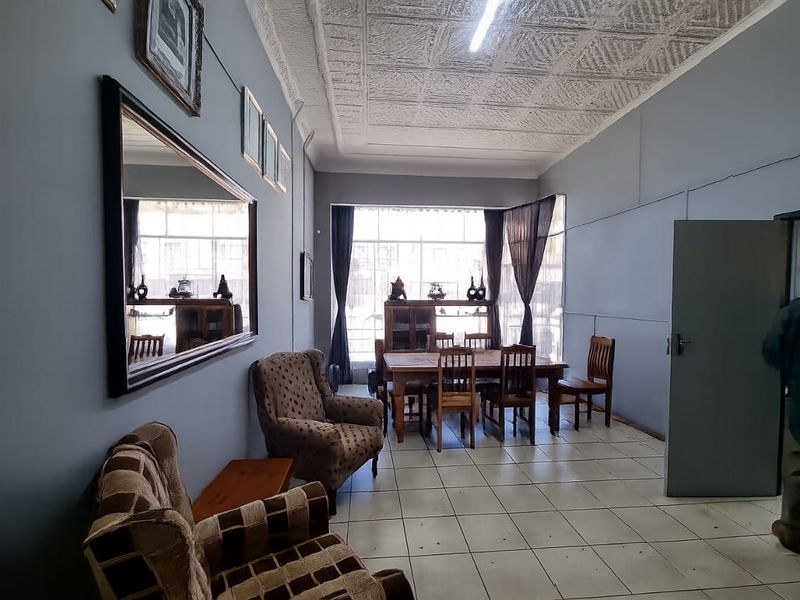 A spacious living area featuring tiled flooring and a textured ceiling, offering a functional layout with natural light from a large window.