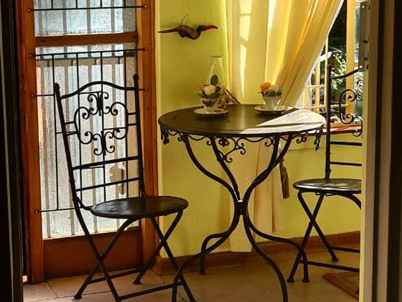 A sunlit enclosed patio area featuring tiled flooring, a timber door frame, and a security gate, offering a bright and inviting transition space.