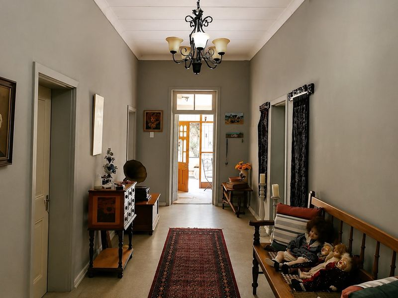 A well-maintained interior hallway featuring a classic wrought iron chandelier and timber panelled ceiling, leading towards the main entrance.