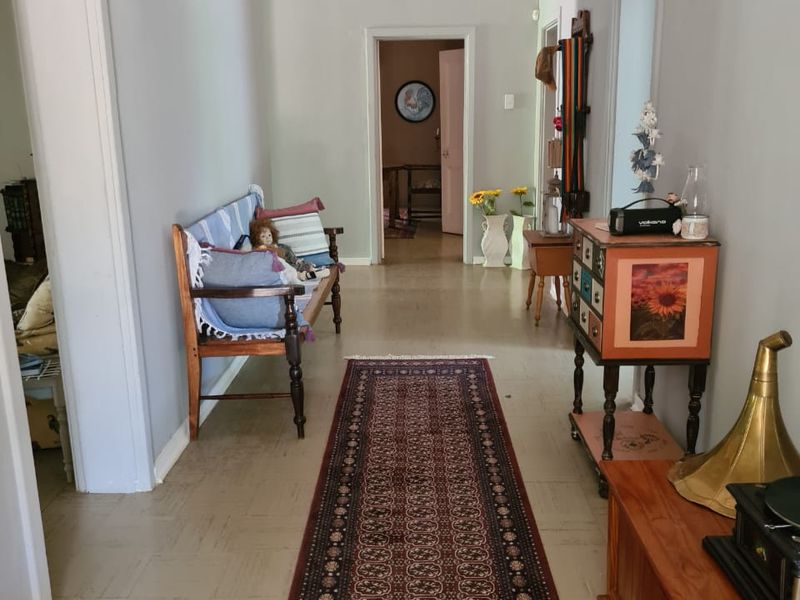 A spacious hallway featuring neutral wall tones, traditional architraves, and original flooring, providing access to multiple rooms within the home.