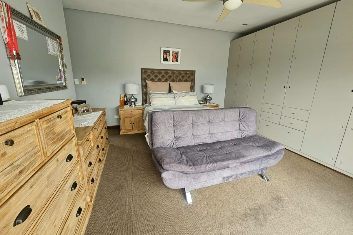 Spacious bedroom featuring extensive built-in cabinetry and a ceiling fan, offering ample storage and comfortable living space.
