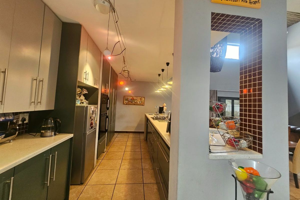 A functional kitchen featuring built-in cabinetry, stone countertops, a gas hob, and a built-in oven, with tiled flooring and a tiled feature wall.