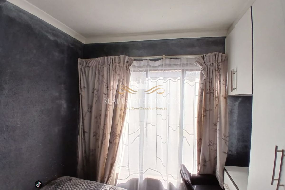 A bedroom featuring built-in cabinetry and a desk, with dark textured wall finishes and natural light through a window.