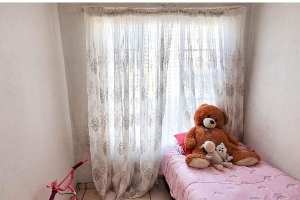 A compact bedroom featuring tiled flooring and a window with curtain rails, requiring minor cosmetic updates to the wall finishes.
