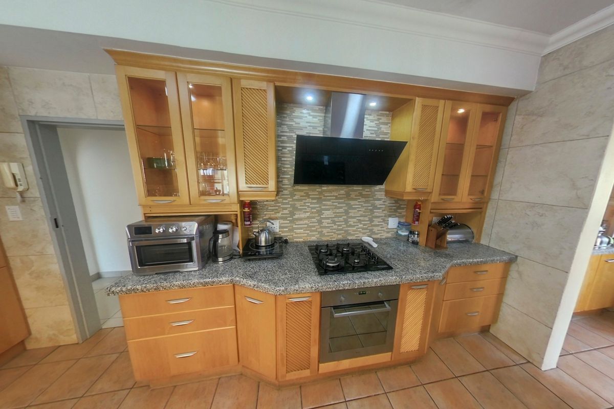 A functional kitchen featuring wooden cabinetry, granite countertops, a gas hob, built-in oven, and a tiled backsplash.