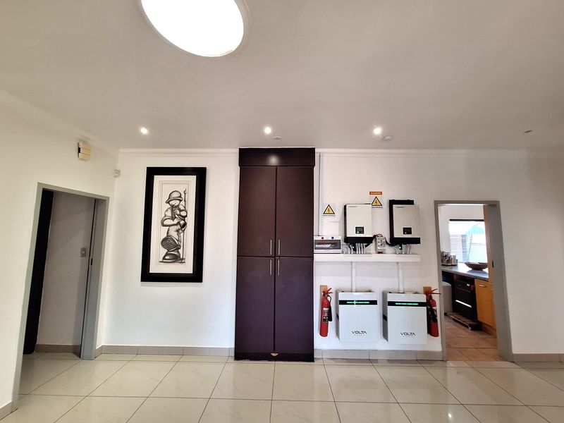 Utility area featuring a modern solar power installation with inverters and battery storage, complemented by built-in cabinetry and tiled flooring.