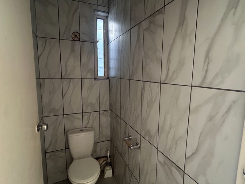 A compact bathroom featuring modern marble-look wall tiles and a standard toilet.