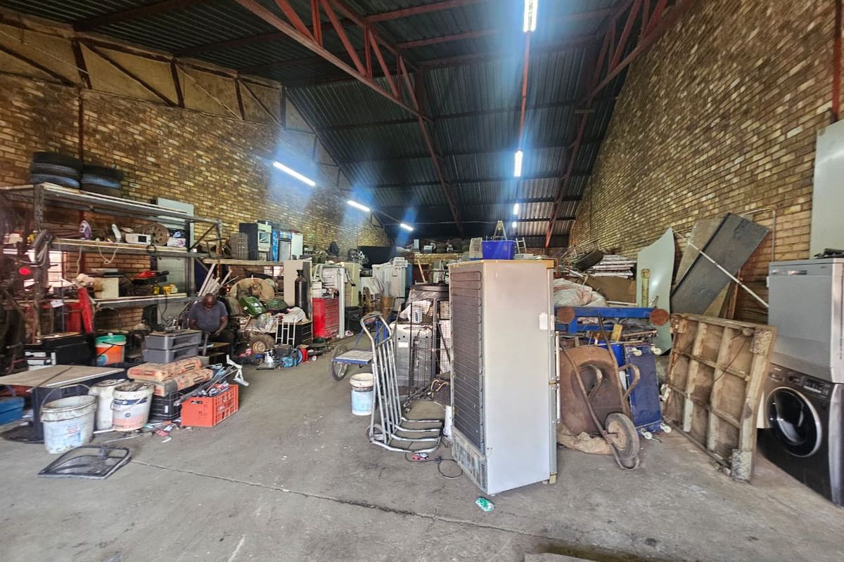 Spacious industrial utility area featuring exposed brick walls, high metal roof trusses, and durable concrete flooring, suitable for workshop or storage use.