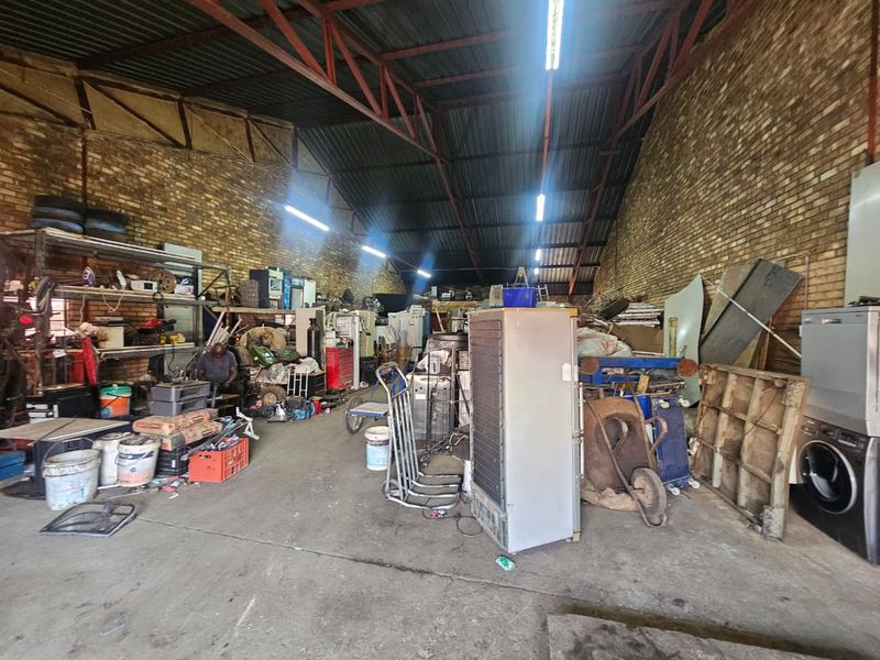 Spacious industrial utility area featuring exposed brick walls, high metal roof trusses, and durable concrete flooring, suitable for workshop or storage use.