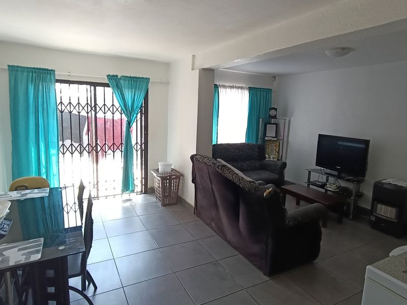 Open plan living and dining area featuring tiled flooring and a sliding door with a security gate leading to the exterior.