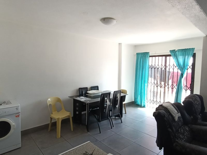 Open plan living and dining area featuring tiled flooring and a security gate leading to the exterior.