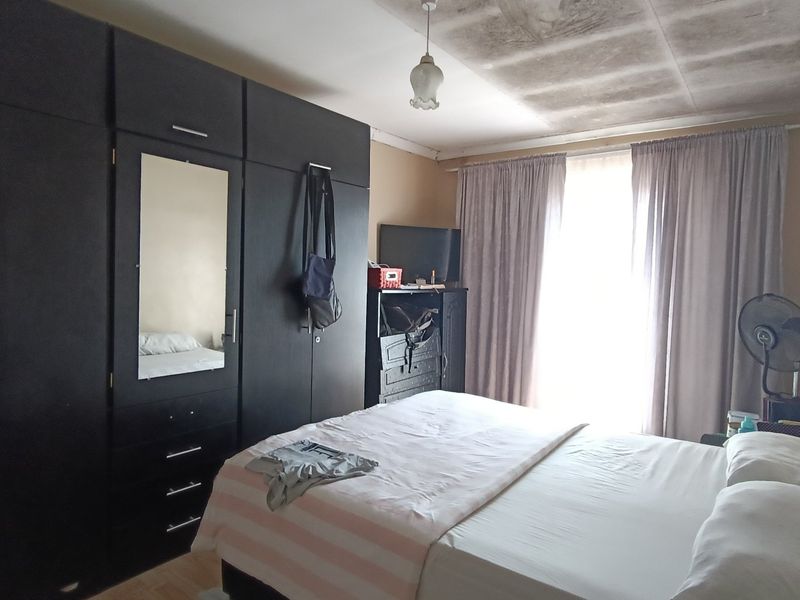 A bedroom featuring built-in cupboards, with visible water damage and staining on the ceiling requiring maintenance.