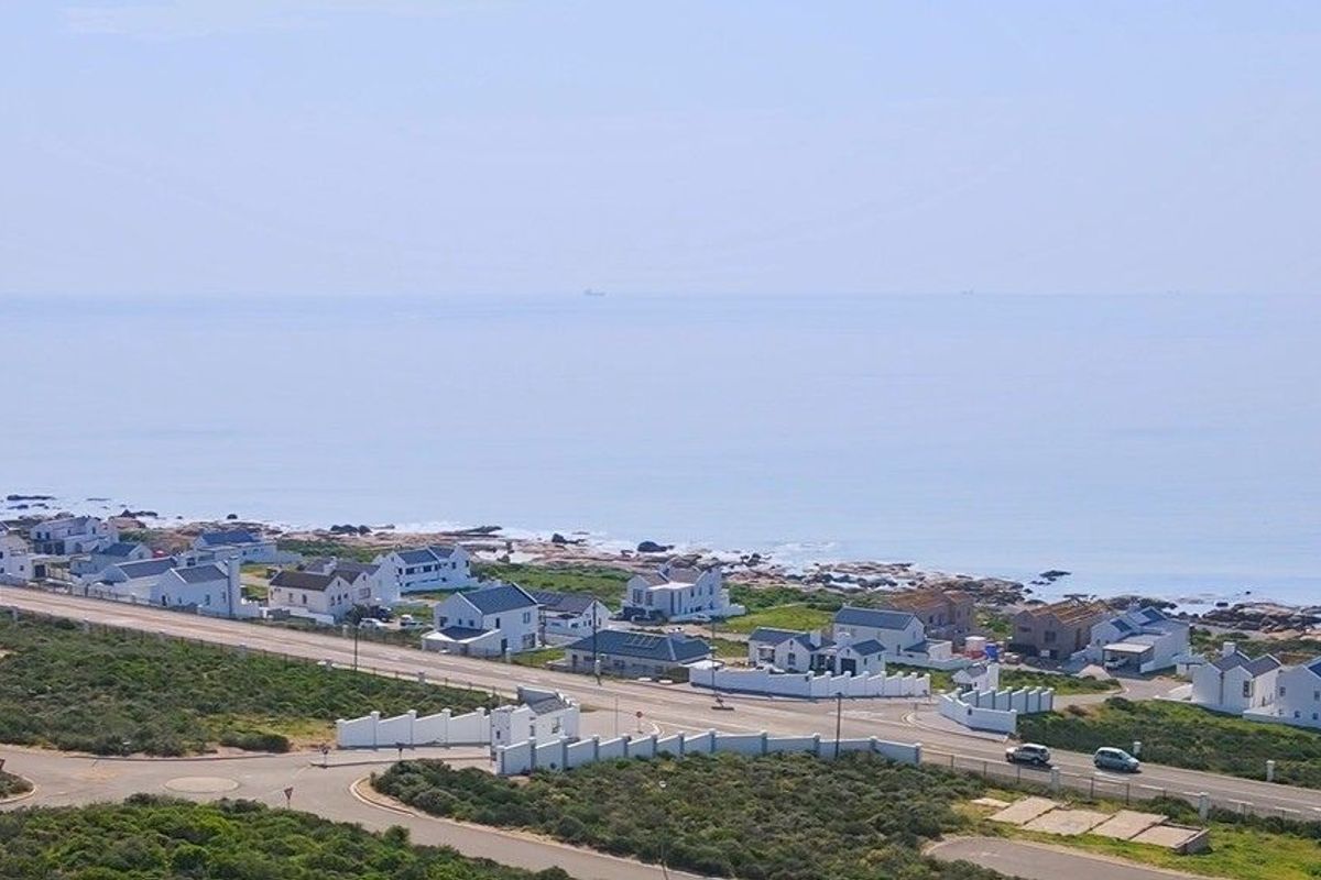 An aerial view of a coastal residential area, showcasing the proximity of the properties to the ocean and local road infrastructure.