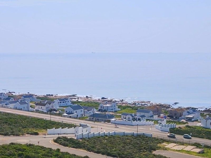 An aerial view of a coastal residential area, showcasing the proximity of the properties to the ocean and local road infrastructure.