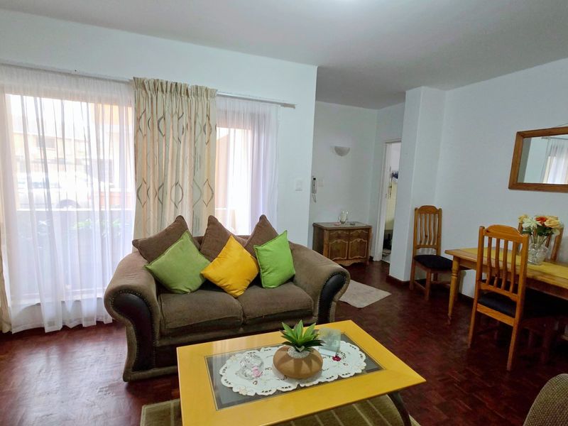 Open plan living and dining area featuring dark parquet flooring and a large sliding glass door providing access to the balcony.