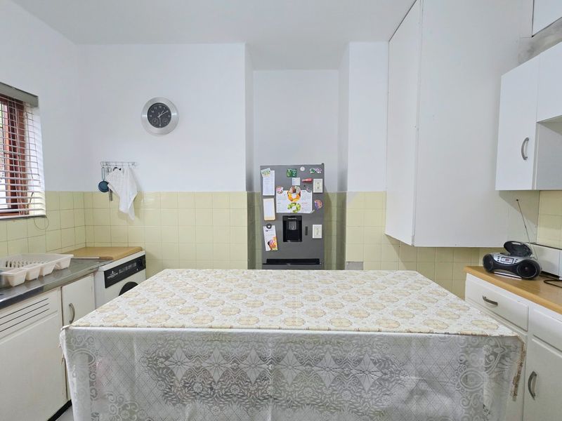 A functional kitchen featuring built-in cabinetry, laminate countertops, a stainless steel sink, and a tiled backsplash, offering a practical layout for daily use.