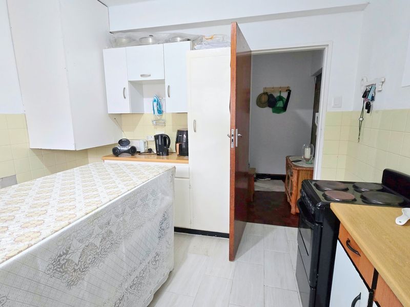 Functional kitchen featuring built-in cabinetry, laminate countertops, tiled backsplash, and an electric stove, offering a practical layout for daily meal preparation.