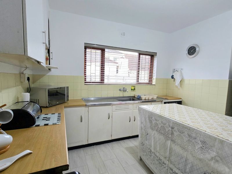 Functional kitchen featuring laminate countertops, stainless steel sink, tiled backsplash, and ample built-in cabinetry with a window for natural light.
