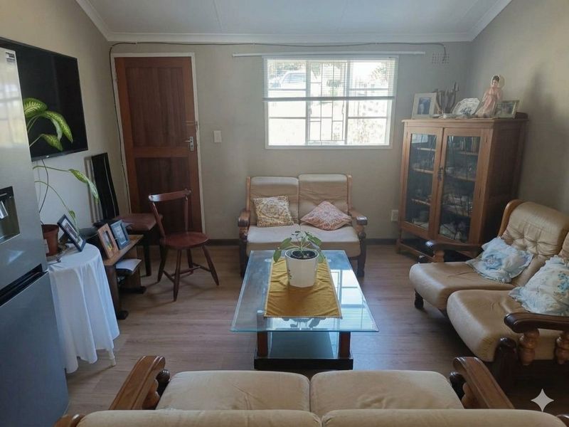 A living room featuring laminate flooring, a timber door, and an aluminium window frame, providing a functional and lived-in space.