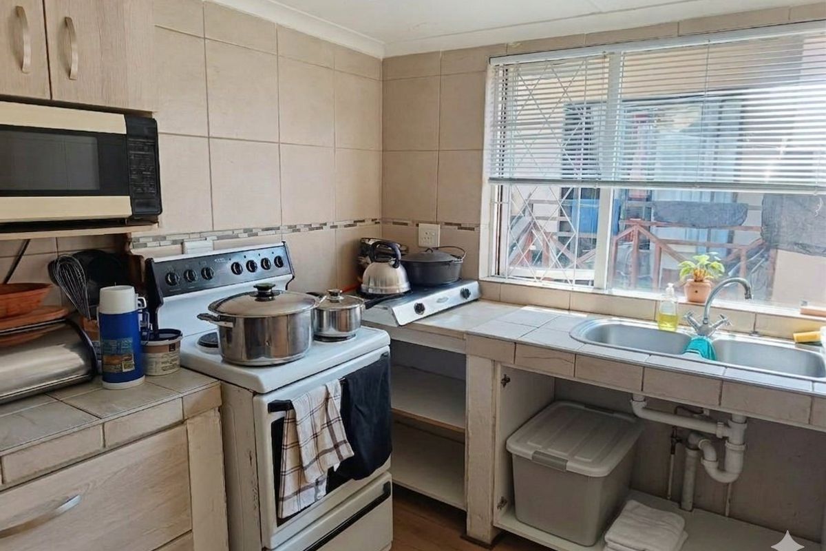 Functional kitchen featuring tiled backsplash, double bowl sink, built-in cabinetry, and a freestanding stove with an integrated microwave.
