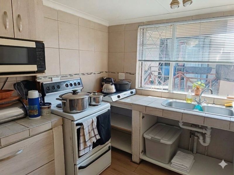Functional kitchen featuring tiled backsplash, double bowl sink, built-in cabinetry, and a freestanding stove with an integrated microwave.