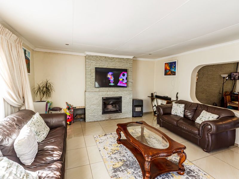 Spacious living room featuring a prominent stone-clad fireplace, tiled flooring, and an arched entryway leading to adjacent living spaces.