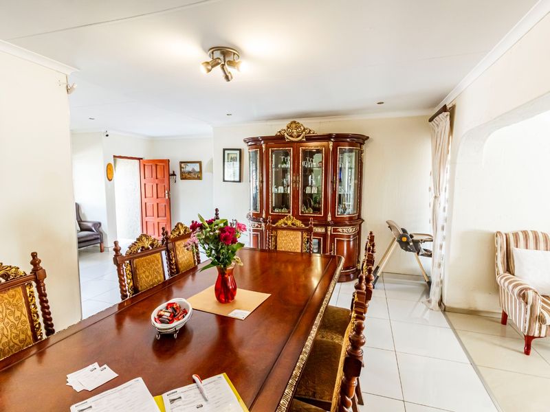 Spacious dining room featuring neutral tiled flooring, recessed lighting, and a classic cove cornice finish, providing a functional space for family meals.