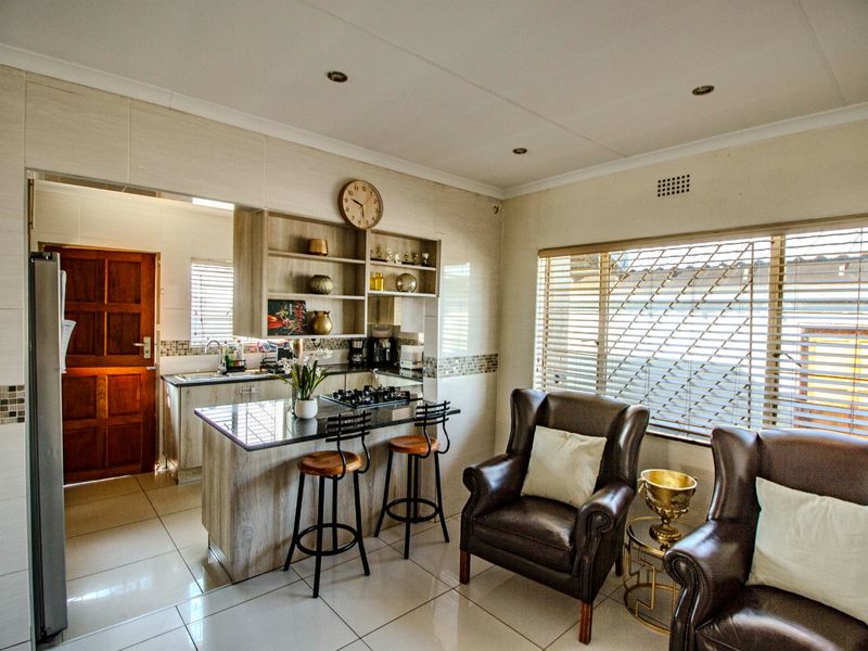 Open plan kitchen and living area featuring tiled flooring, granite countertops, built-in cabinetry, and a gas hob with integrated breakfast bar seating.