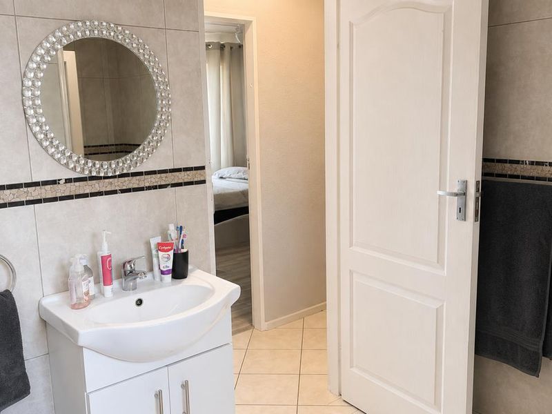 A well-maintained bathroom featuring a vanity cabinet with a ceramic basin, tiled walls with decorative accents, and neutral floor tiles.