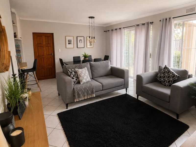 An open-plan living and dining area featuring tiled flooring, neutral walls, and sliding glass doors that provide access to the outdoor space.