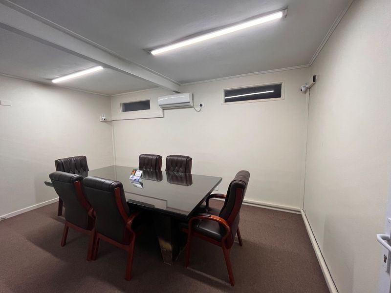 A functional office meeting room featuring carpeted flooring, split-system air conditioning, and integrated security surveillance.