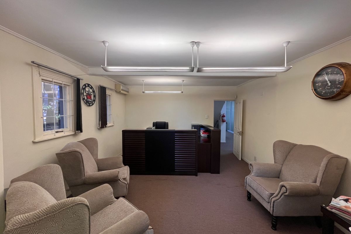 A functional commercial office space featuring a reception desk, carpeted flooring, and overhead fluorescent lighting, suitable for a professional business environment.