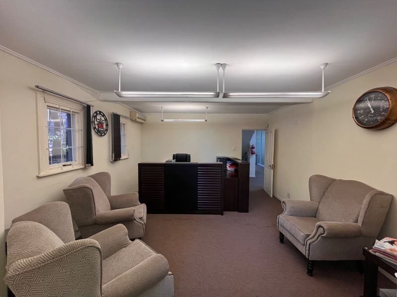 A functional commercial office space featuring a reception desk, carpeted flooring, and overhead fluorescent lighting, suitable for a professional business environment.