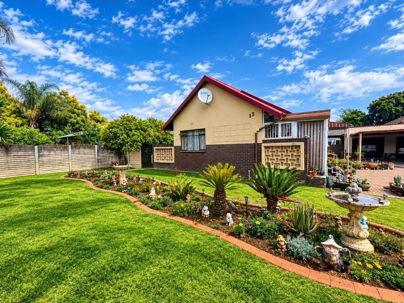 Front view of a well-maintained house featuring a landscaped garden, paved driveway, and brick exterior finishes.